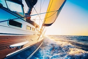 A sailboat glides swiftly through blue ocean waves at sunset, with sunlight reflecting off the deck and yellow sails catching the wind—much like the steady guidance provided by skilled Compensation Lawyers.