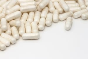 A pile of white capsules spread across a white surface, with some capsules separated from the group—an image highlighting issues that may relate to Medical Negligence Compensation.