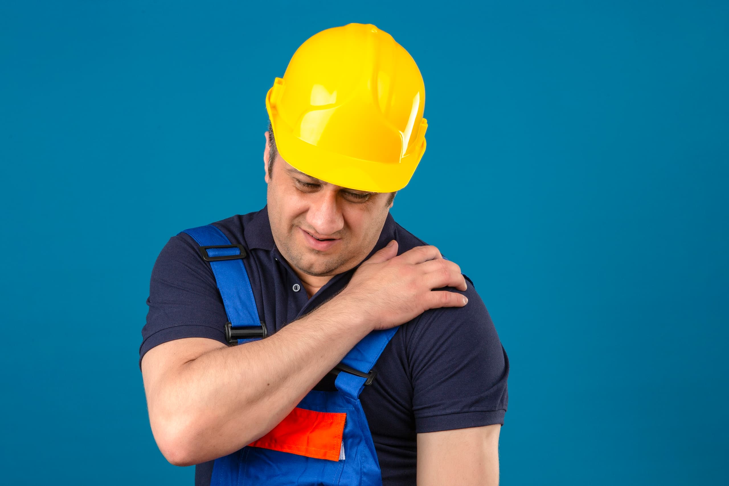 constructor middle aged man wearing construction uniform and safety helmet touching shoulder having pain over isolated blue background