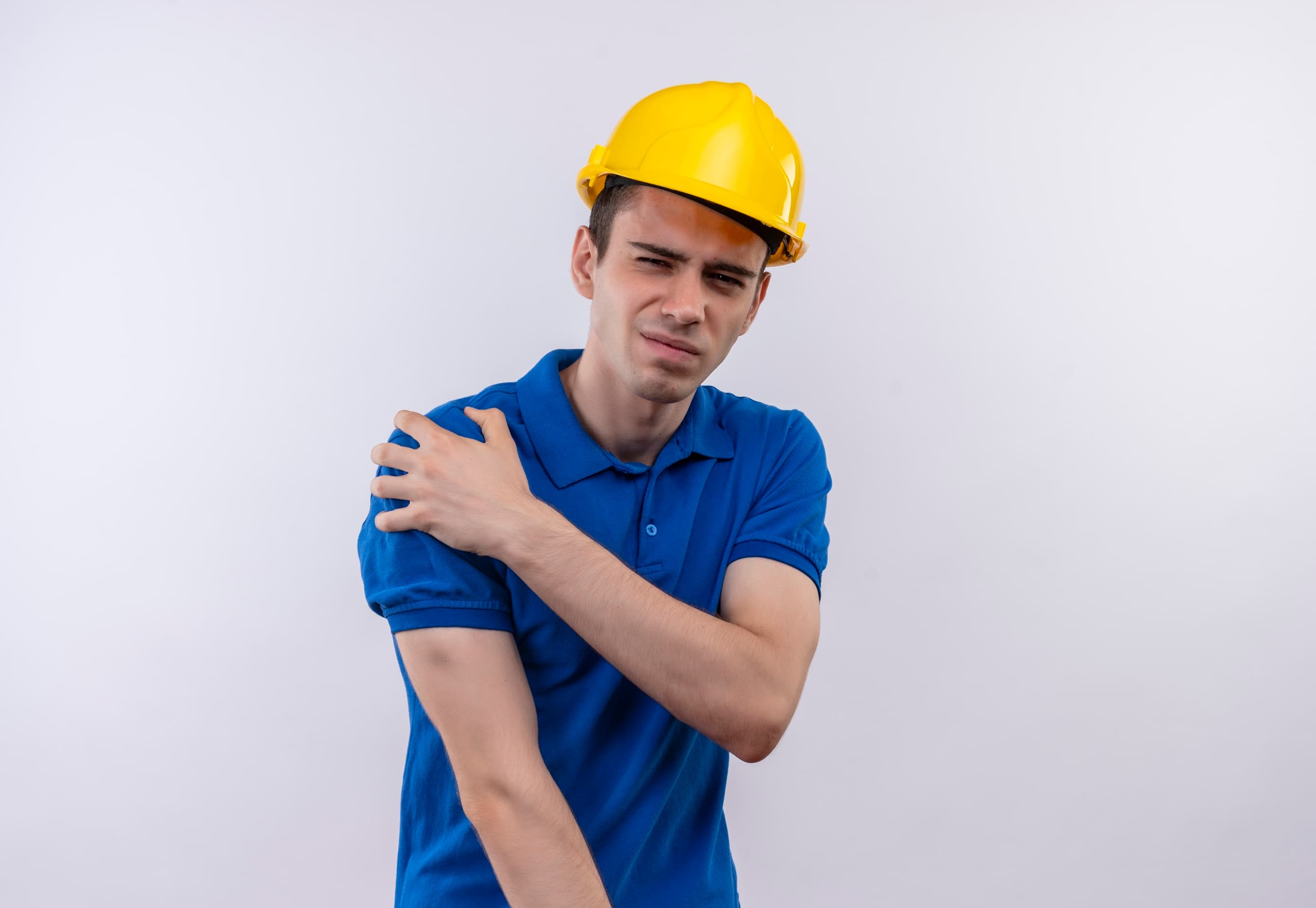 young builder man wearing construction uniform and safety helmet doing unhappy face and suffers from pain over white isolated background